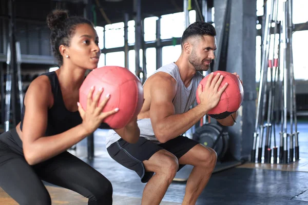 Hermosa pareja de jóvenes deportes está trabajando con la pelota de la medicina en el gimnasio. — Foto de Stock