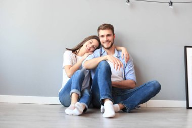 Gri duvarın arka planda oturan mutlu çift.