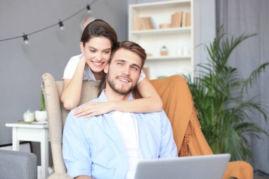 Genç çift evde bazı online alışveriş yapıyor, kanepede bir dizüstü bilgisayar kullanarak.