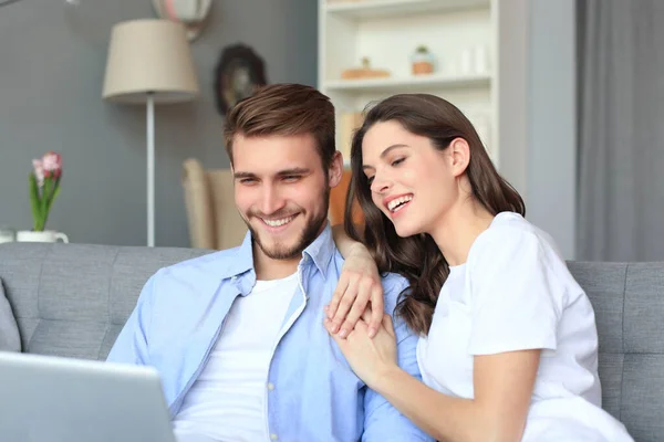 Giovane coppia fare shopping online a casa, utilizzando un computer portatile sul divano . — Foto Stock