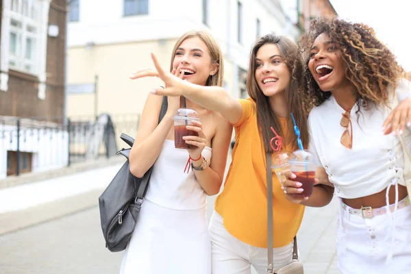 Três meninas hipster cool na moda, amigos bebem coquetel no fundo da cidade urbana. — Fotografia de Stock