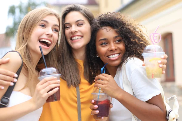 Trzy modne hipsterskie dziewczyny, przyjaciele piją koktajl w miejskim tle. — Zdjęcie stockowe