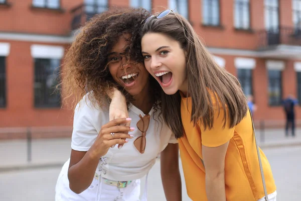 Deux jeunes femmes hipster souriantes en vêtements d'été posant dans la rue.Femme montrant des émotions faciales positives . — Photo