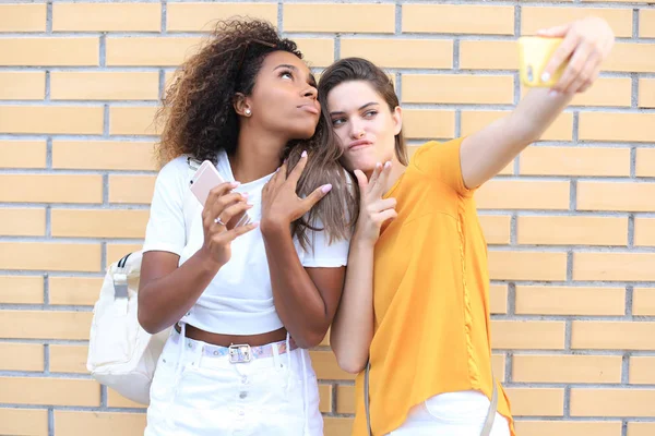 Dos jóvenes mujeres hipster sonrientes en ropa de verano posando en la calle.Femenina mostrando emociones positivas en la cara . —  Fotos de Stock