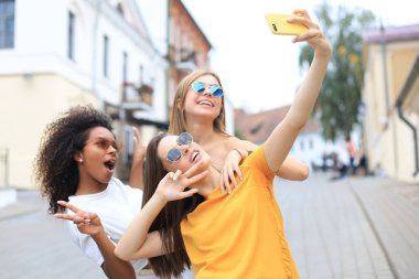 Üç tatlı kız arkadaş birlikte eğleniyor, şehirde selfie çekiyorlar..