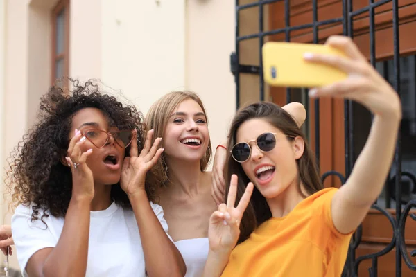 Tři roztomilé mladé dívky přátelé baví spolu, přičemž selfie ve městě. — Stock fotografie