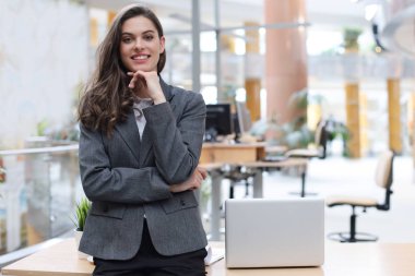 Ofiste masanın yanında duran çekici bir iş kadını..