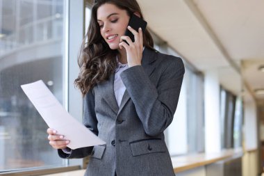Ofiste akıllı telefon kullanan gülümseyen bir iş kadını..