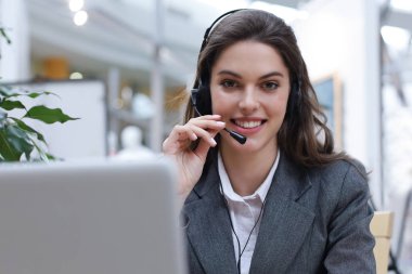 Kulaklıklı ve gülümseyen kadın müşteri destek operatörü.