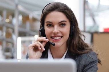 Kulaklıklı ve gülümseyen kadın müşteri destek operatörü.