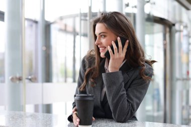 Ofiste akıllı telefon kullanan gülümseyen bir iş kadını..