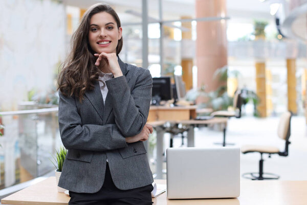 Attractive businesswoman standing near desk in the office.