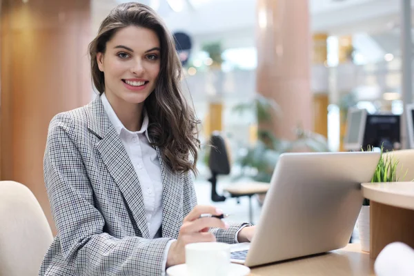 Portrait d'une jeune femme d'affaires joyeuse assise à la table au bureau et regardant la caméra. — Photo