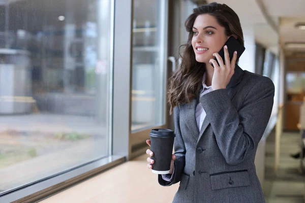 Jovem mulher de negócios sorrindo usando smartphone no escritório . — Fotografia de Stock