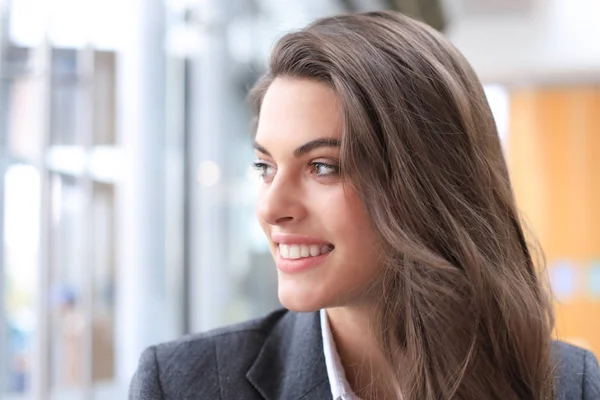 Aantrekkelijke zakenvrouw die glimlacht terwijl ze op kantoor staat. — Stockfoto