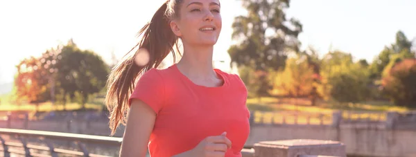 Beautiful young woman in sports clothing running while exercising outdoors.