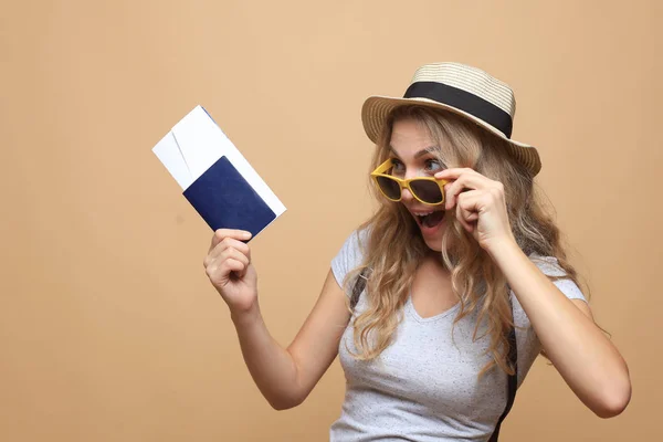 Schöne blonde Frau mit Sonnenbrille posiert mit Pass und Eintrittskarten vor beigem Hintergrund. — Stockfoto