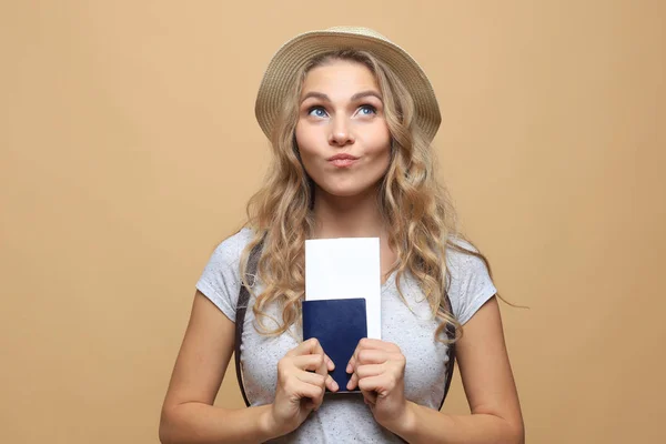 Mooie blonde vrouw in de zomer kleding poseren met paspoort met tickets over beige achtergrond. — Stockfoto