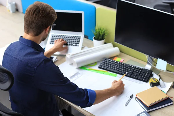 Skjuten av en stilig manlig arkitekt som arbetar med en design på sitt kontor. — Stockfoto