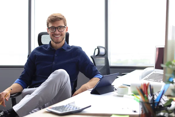 Молодой бизнесмен, работающий на планшете, сидя в офисе. — стоковое фото