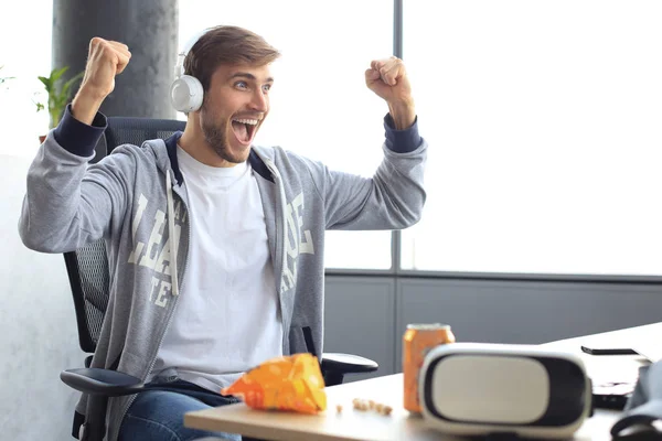 Portret van extatische gamer man in hoofdtelefoon schreeuwen en verheugen tijdens het spelen van videospelletjes op de computer. — Stockfoto