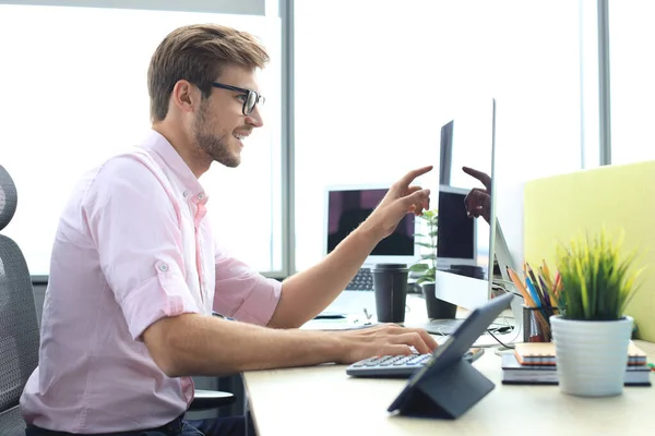 Jeune homme d'affaires réfléchi en chemise travaillant à l'aide d'un ordinateur tout en se tenant dans le bureau . — Photo