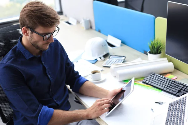 Pensativo joven hombre de negocios que trabaja usando la computadora mientras está de pie en la oficina . — Foto de Stock