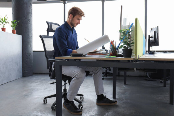 Красивый молодой бизнесмен рисует что-то во время работы в офисе.