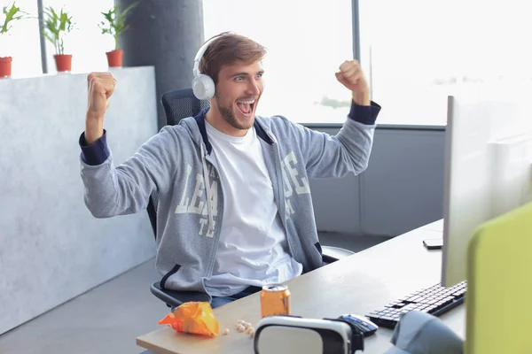 Portret ekstatycznego gracza w słuchawkach krzyczący i radujący się podczas gry wideo na komputerze. — Zdjęcie stockowe