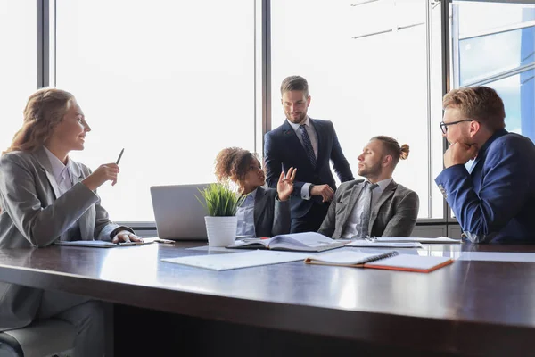 Groupe de jeunes gens modernes en tenue de cérémonie souriant et discutant de quelque chose tout en travaillant dans le bureau moderne — Photo