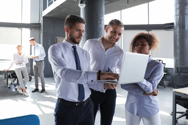 Gruppo di uomini d'affari moderni stanno lavorando con il computer portatile e sorridente mentre in piedi nel corridoio dell'ufficio — Foto Stock