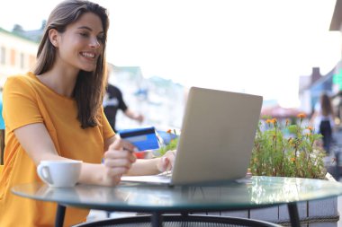 Açık kafede kredi kartı ve laptop kullanan mutlu bir esmer..