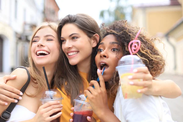 Τρία μοντέρνα cool hipster κορίτσια, οι φίλοι πίνουν κοκτέιλ στο αστικό φόντο της πόλης. — Φωτογραφία Αρχείου