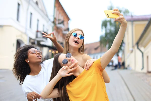 Tres amigas jóvenes lindas divirtiéndose juntas, tomando una selfie en la ciudad . — Foto de Stock