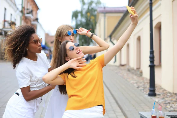 Trois jolies jeunes filles amies s'amusent ensemble, prenant un selfie à la ville . — Photo