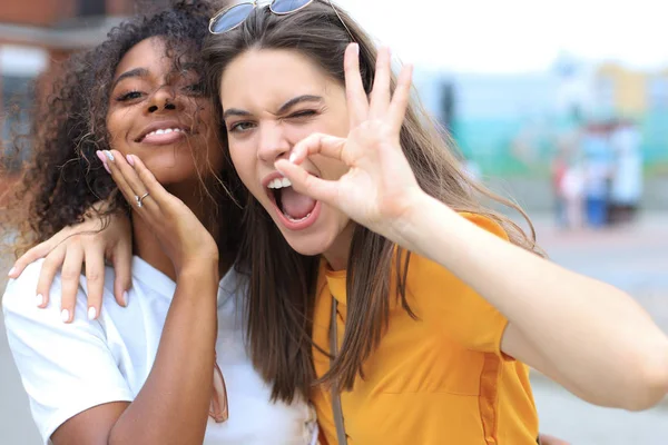 Dvě mladé usmívající se hipster ženy v letních šatech pózují na ulici.Žena vykazující pozitivní tvář emoce. — Stock fotografie