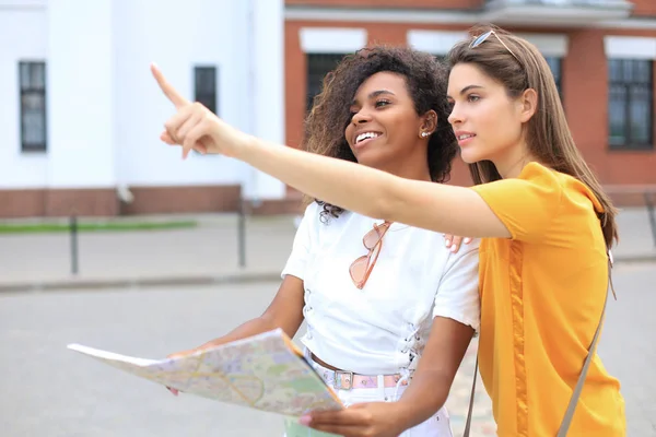 Fotografie dvou dívek, jak si užívají prohlídku přírody. Krásné ženské turistické objevování města s mapou. — Stock fotografie