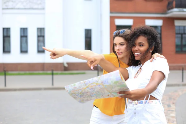 Vacaciones y concepto de turismo - hermosas chicas en busca de dirección en la ciudad . —  Fotos de Stock