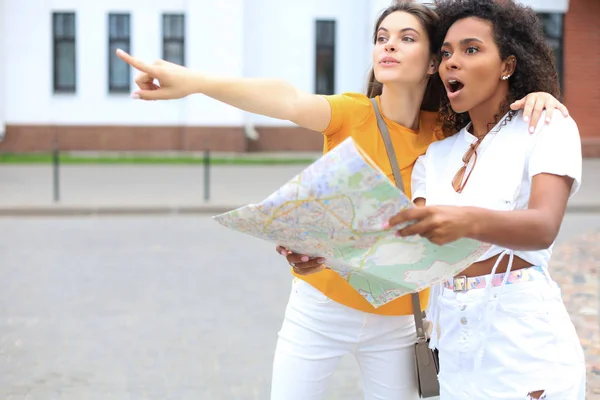 Férias e conceito de turismo - meninas bonitas que procuram direção na cidade . — Fotografia de Stock