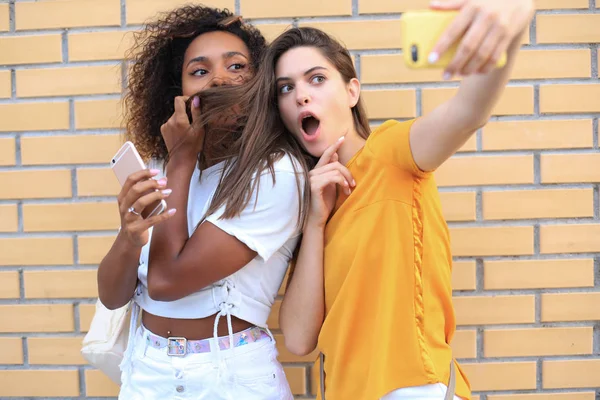 Deux jeunes femmes hipster souriantes en vêtements d'été posant dans la rue.Femme montrant des émotions faciales positives . — Photo