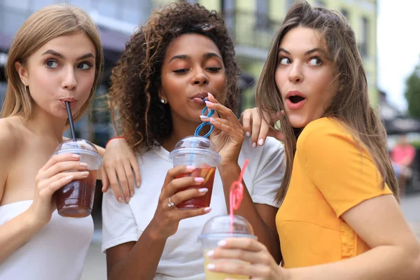 Três meninas hipster cool na moda, amigos bebem coquetel no fundo da cidade urbana. — Fotografia de Stock