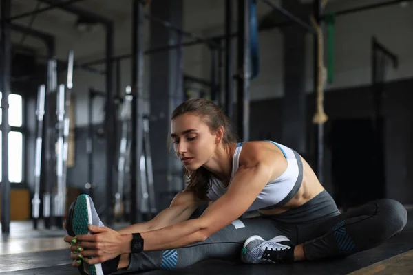 Jovem mulher esportiva que se estende no ginásio. — Fotografia de Stock