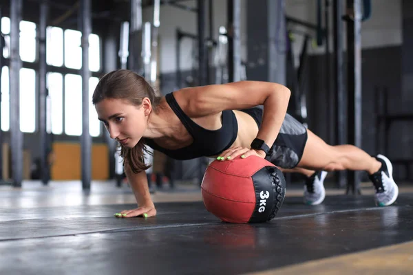 Fit y la mujer muscular haciendo ejercicio con balón de medicina en el gimnasio. —  Fotos de Stock