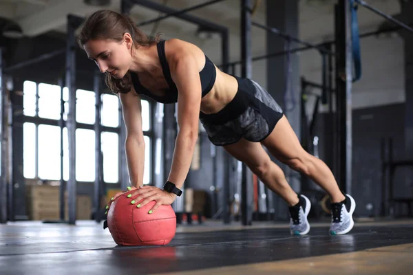 Donna in forma e muscolosa che si allena con la palla medica in palestra. — Foto Stock