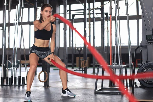 Fit vrouw met behulp van battle touwen tijdens krachttraining in de sportschool. — Stockfoto