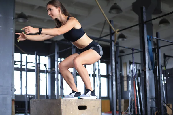 Jovem atleta feminina pulando na caixa em um ginásio crossfit . — Fotografia de Stock