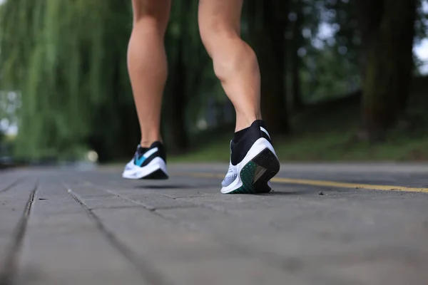 Runner feet running on road closeup on shoe, outdoor at sunset or sunrise.
