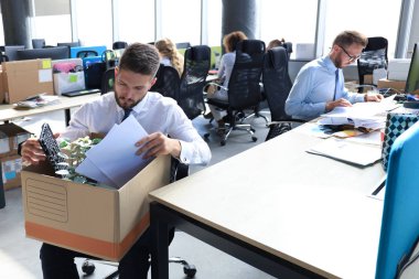 Sad dismissed worker are taking his office supplies with him from office clipart