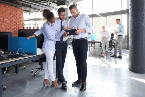 Gruppe moderner Geschäftsleute spricht und lächelt, während sie im Büroflur steht — Stockfoto