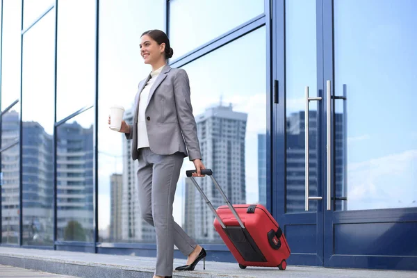 Portrait of successful business woman traveling with case at airport. Beautiful stylish female travel with luggage.